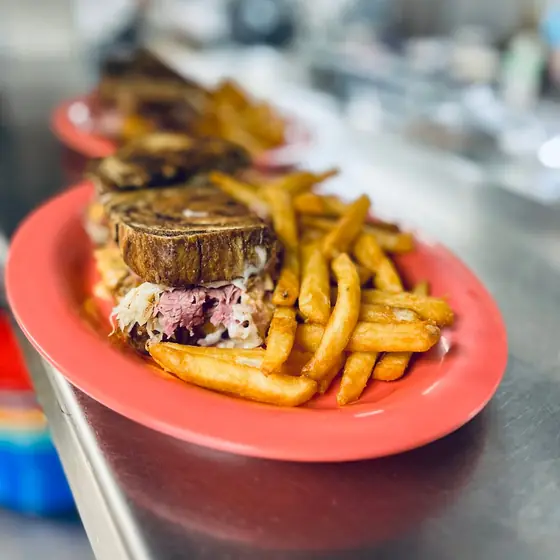 Reuben sandwich on marble rye with fries on a coral plate